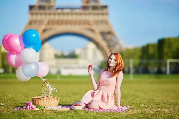 Γυναίκα σε ροζ φόρεμα με μάτσο μπαλόνια έχοντας πικ-νικ, κοντά στον Πύργο του Άιφελ στο Παρίσι — Φωτογραφία Αρχείου