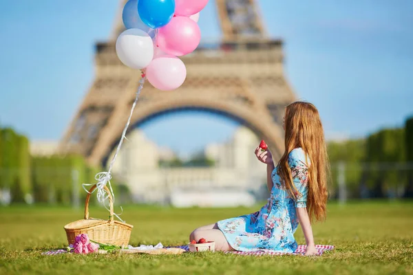 Donna in abito rosa con mazzo di palloncini che fanno un picnic vicino alla torre Eiffel a Parigi — Foto Stock