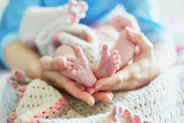 Mor håller nyfödd bebis fötter i hennes händer — Stockfoto