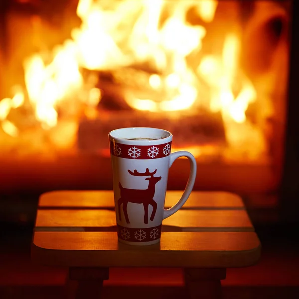 Copa de chocolate caliente y malvaviscos cerca de la chimenea — Foto de Stock