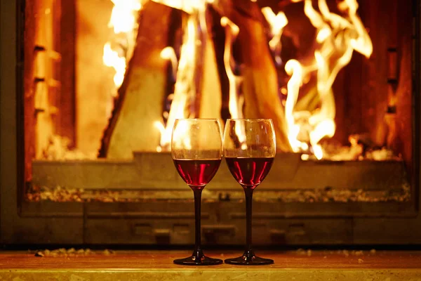Two glasses of red wine near fireplace — Stock Photo, Image