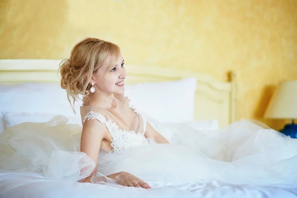 Veselá mladá nevěsta ve svatebních šatech v hotelovém pokoji — Stock fotografie