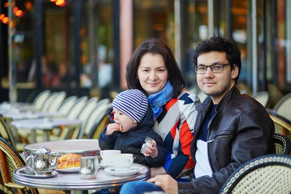 Счастливая семья из трех человек в парижском открытом кафе — стоковое фото