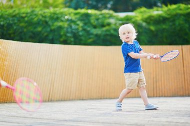 Küçük çocuk parkta badminton oynarken