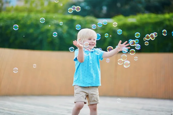 Kleine jongen speelt met bubbels buitenshuis — Stockfoto