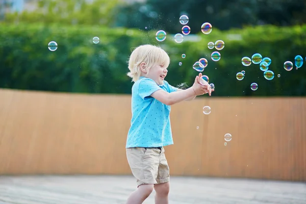 Kleine jongen speelt met bubbels buitenshuis — Stockfoto