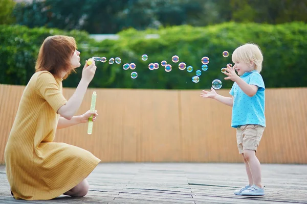 Matka vyfukování bublin a hrát si s její malý syn — Stock fotografie