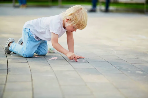 Kleiner Junge zeichnet mit Kreide auf Asphalt — Stockfoto