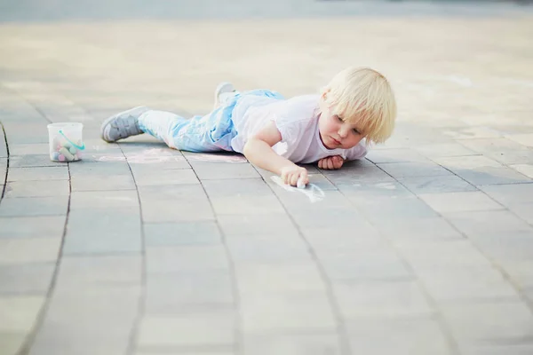 Kleiner Junge zeichnet mit Kreide auf Asphalt — Stockfoto