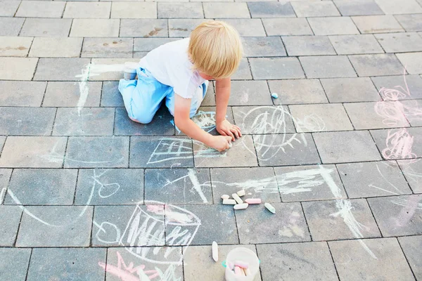 Kleiner Junge zeichnet mit Kreide auf Asphalt — Stockfoto