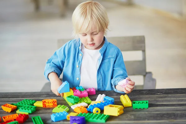 Kleiner Junge spielt mit bunten Plastikbausteinen — Stockfoto