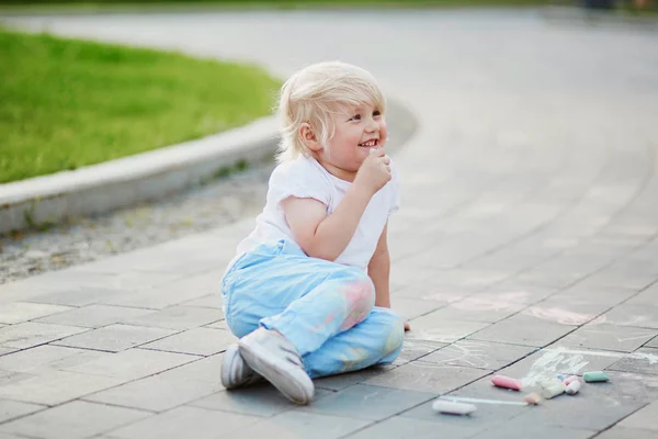 Kleiner Junge zeichnet mit Kreide auf Asphalt — Stockfoto