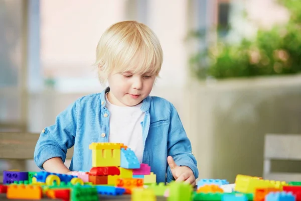 Маленький мальчик играет с красочными пластиковыми блоками — стоковое фото