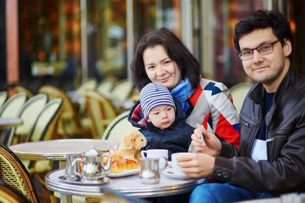Счастливая семья из трех человек в парижском открытом кафе — стоковое фото