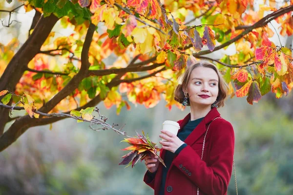 Mujer joven con racimo de hojas de otoño de colores y café — Foto de Stock