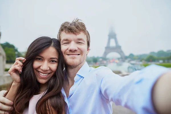 Pareja feliz tomando selfie cerca de la torre Eiffel — Foto de Stock
