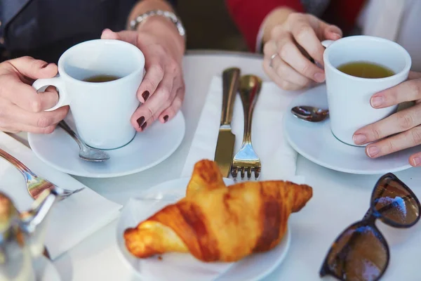 Две девушки в парижском кафе под открытым небом, пьют кофе с круассаном — стоковое фото