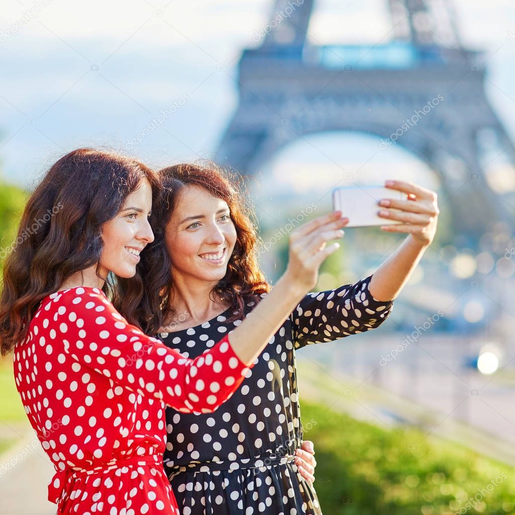 Twin sisters taking selfie near the Eiffel tower in Paris