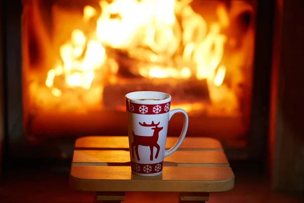 Kopje warme chocolademelk en marshmallows in de buurt van open haard — Stockfoto