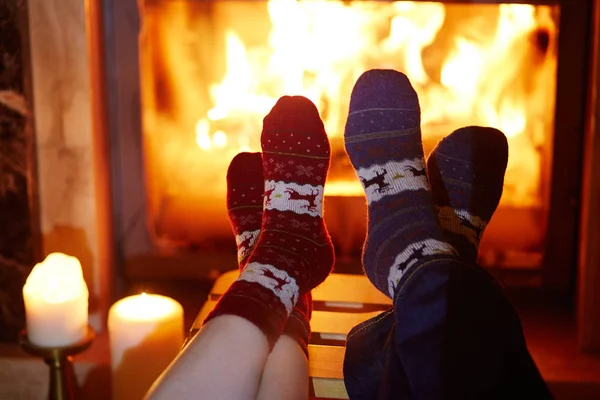 Man en vrouw in warme sokken in de buurt van open haard — Stockfoto