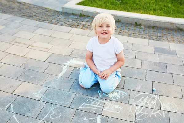 Niño pequeño dibujando con tiza sobre asfalto — Foto de Stock