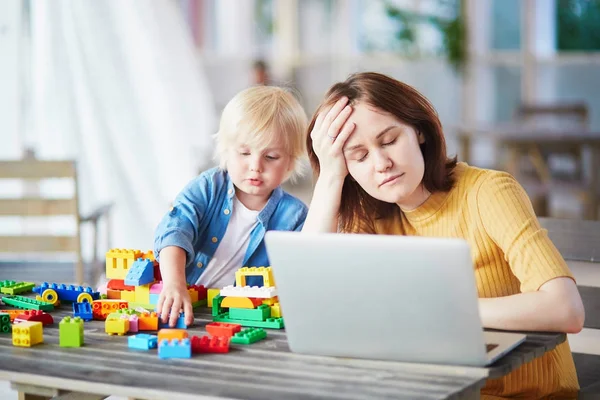 Little boy playing with construction blocks while his mother working on computer — Stock Photo, Image