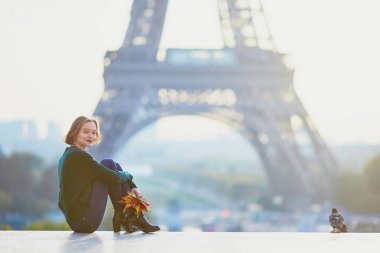 Güzel genç Fransız kadın renkli sonbahar grup ile Paris'te Eyfel Kulesinin yakınında bir sonbahar gününde bırakır
