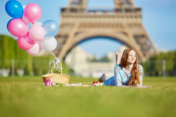 美丽的年轻女人的气球在法国巴黎的埃菲尔铁塔附近野餐一堆粉红色连衣裙 — 图库照片
