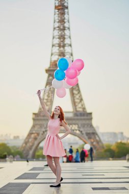 Mutlu genç kız pembe ve mavi balonlar Paris, Fransa'da Eyfel Kulesi önünde sürü