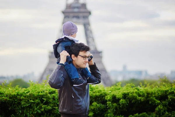 Отец держит сына на плечах у Эйфелевой башни — стоковое фото