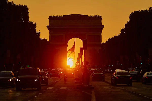 交通堵塞有很多的 Vehices 在巴黎凯旋门与香榭丽舍大街上的和漂亮的日落 在炎热的夏天 太阳就坐落于拱 — 图库照片