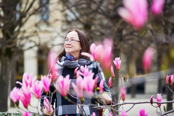 美丽的中年女子在巴黎公园春天天欣赏粉红色白玉兰盛开 — 图库照片