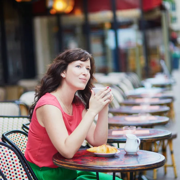 美しい若い女性とパリの屋外カフェでおいしいクロワッサンを食べてコーヒーを飲んで — ストック写真