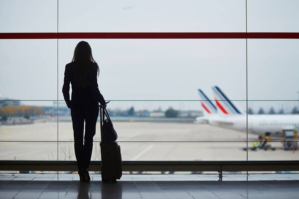 Young woman in international airport looking at planes through the window