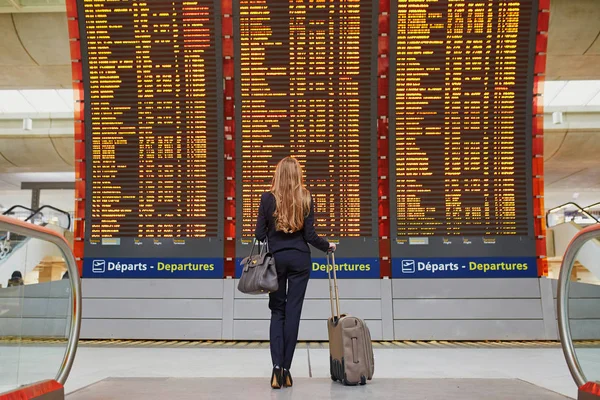 国际机场的年轻妇女在大信息显示附近 — 图库照片
