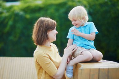 Genç anne küçük yürümeye başlayan çocuk oğlu ile parkta oynarken açık havada yaz gününde
