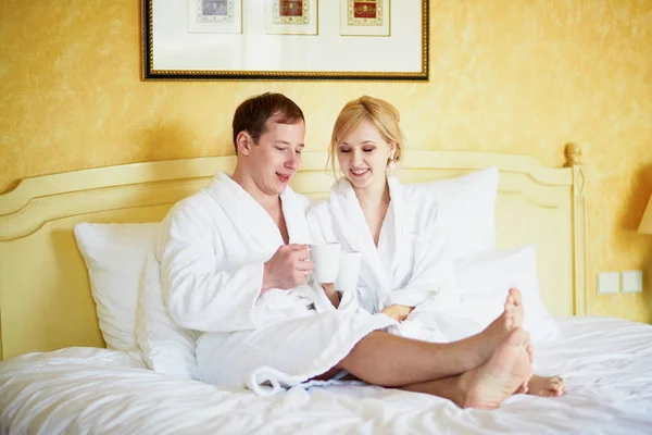 Gelukkige Jonge Paar Witte Badjassen Drinken Koffie Samen Bed Ochtend — Stockfoto