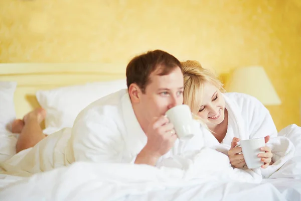 Gelukkige Jonge Paar Witte Badjassen Drinken Koffie Samen Bed Ochtend — Stockfoto