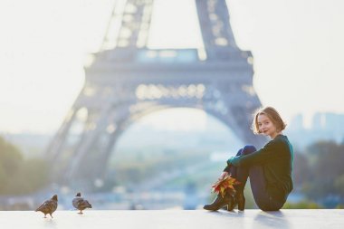 Güzel genç Fransız kadın renkli sonbahar grup ile Paris'te Eyfel Kulesinin yakınında bir sonbahar gününde bırakır