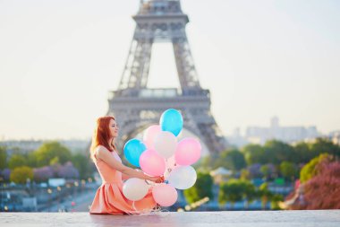 Mutlu genç kız pembe ve mavi balonlar Paris, Fransa'da Eyfel Kulesi önünde sürü