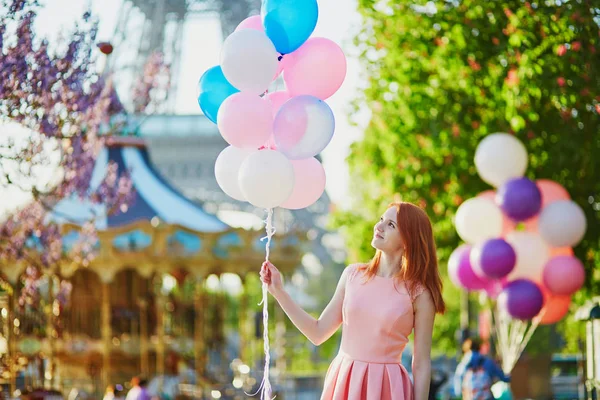 エッフェル塔とパリ フランスでメリーゴーランドの前でピンクとブルーの風船の束を持つ幸せな少女 — ストック写真