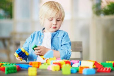 Sevimli küçük çocuk kindergaten veya okul öncesi evde, renkli plastik inşaat bloklarla oynama. Yaratıcı oyun çocuklar için