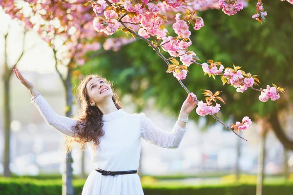 フランスのパリで桜の季節を楽しんでいる白いドレスで幸せな若い女 — ストック写真