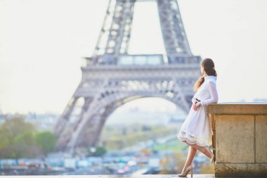 Fransa'nın Paris, Eyfel Kulesi yakınındaki beyaz elbiseli mutlu genç kadın