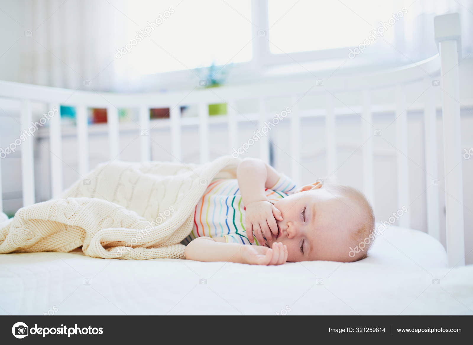 Baby Sleeping In Co Sleeper Crib Attached To Parents Bed Stock