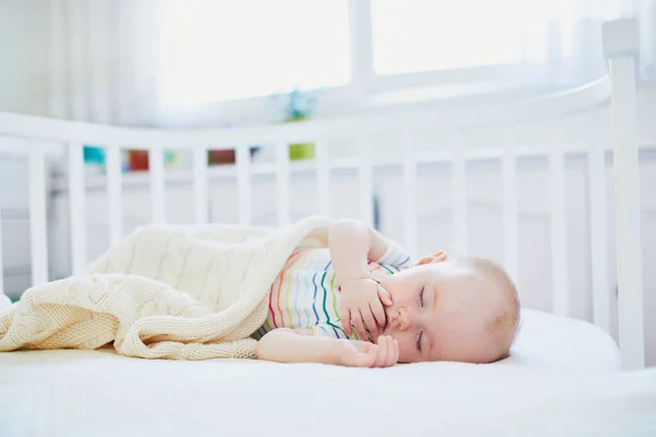 Baby sleeping in co-sleeper crib attached to parents' bed