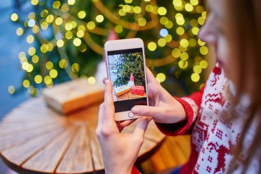 Kahve fincanı ve Noel hediyesinin fotoğrafını çeken kadın
