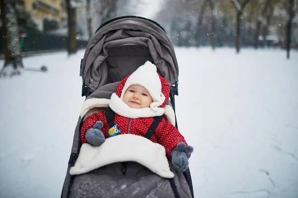 Glad leende Baby flicka i sittvagn i Paris dag med tung snö — Stockfoto