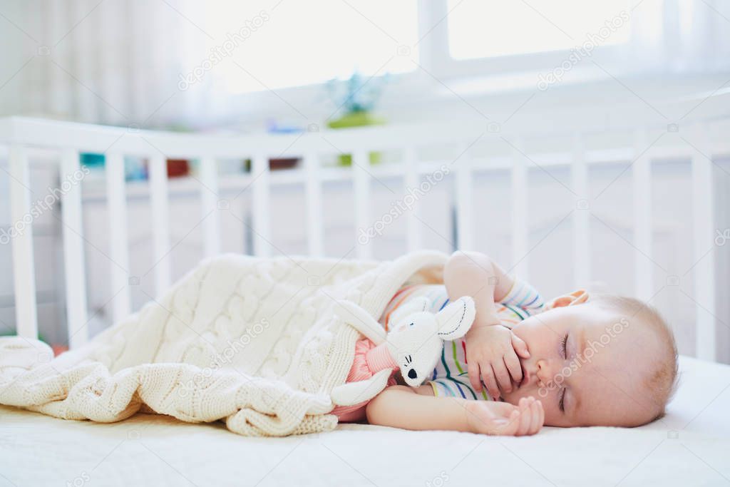 Baby sleeping in co-sleeper crib attached to parents' bed