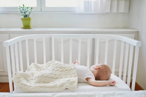 Baby sleeping in co-sleeper crib attached to parents 'bed — стоковое фото